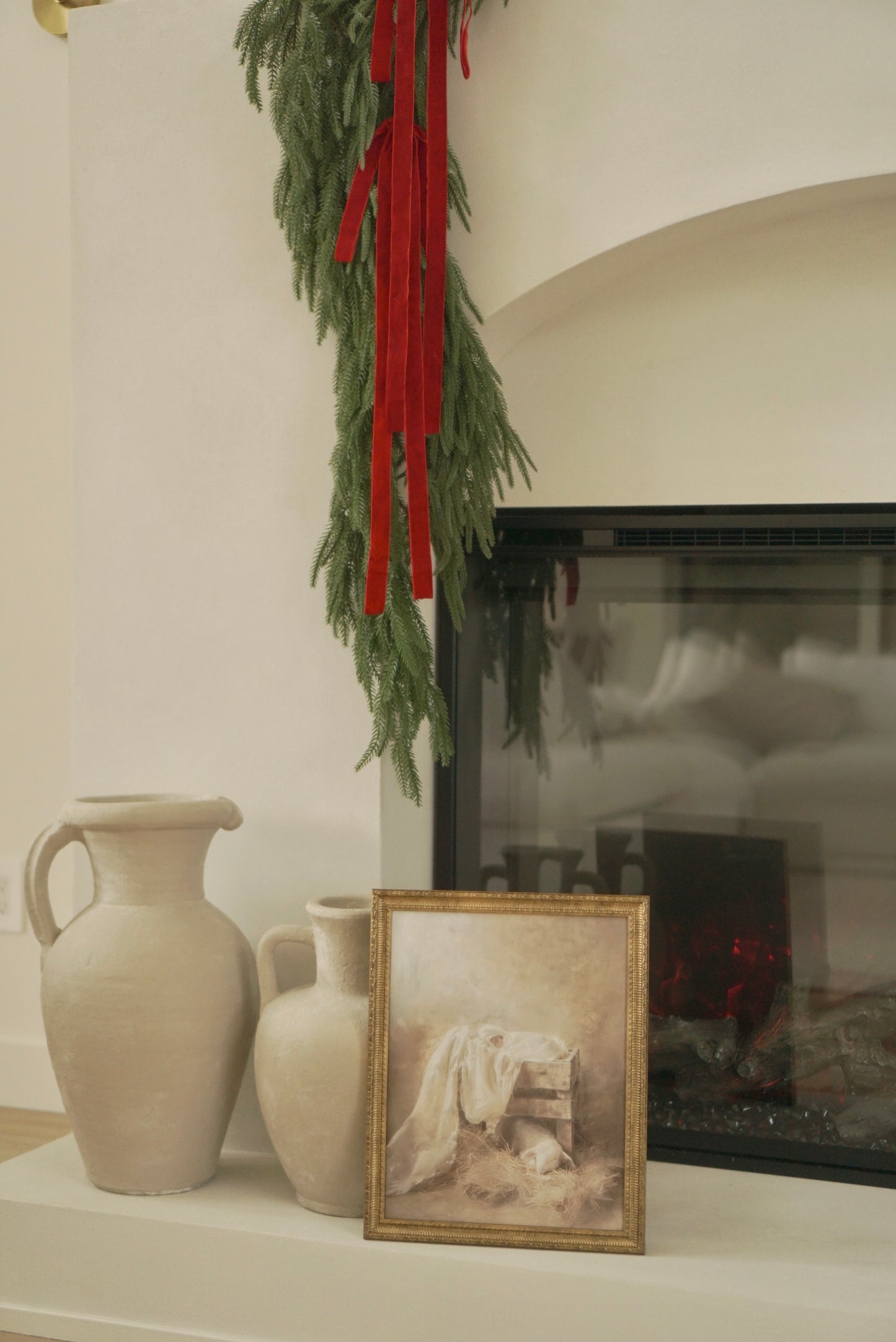 Decorative mantel with vases, a framed picture, and a fireplace with greenery and red ribbons. Christian Christmas artwork made by a christian artist. Nativity scene artwork.