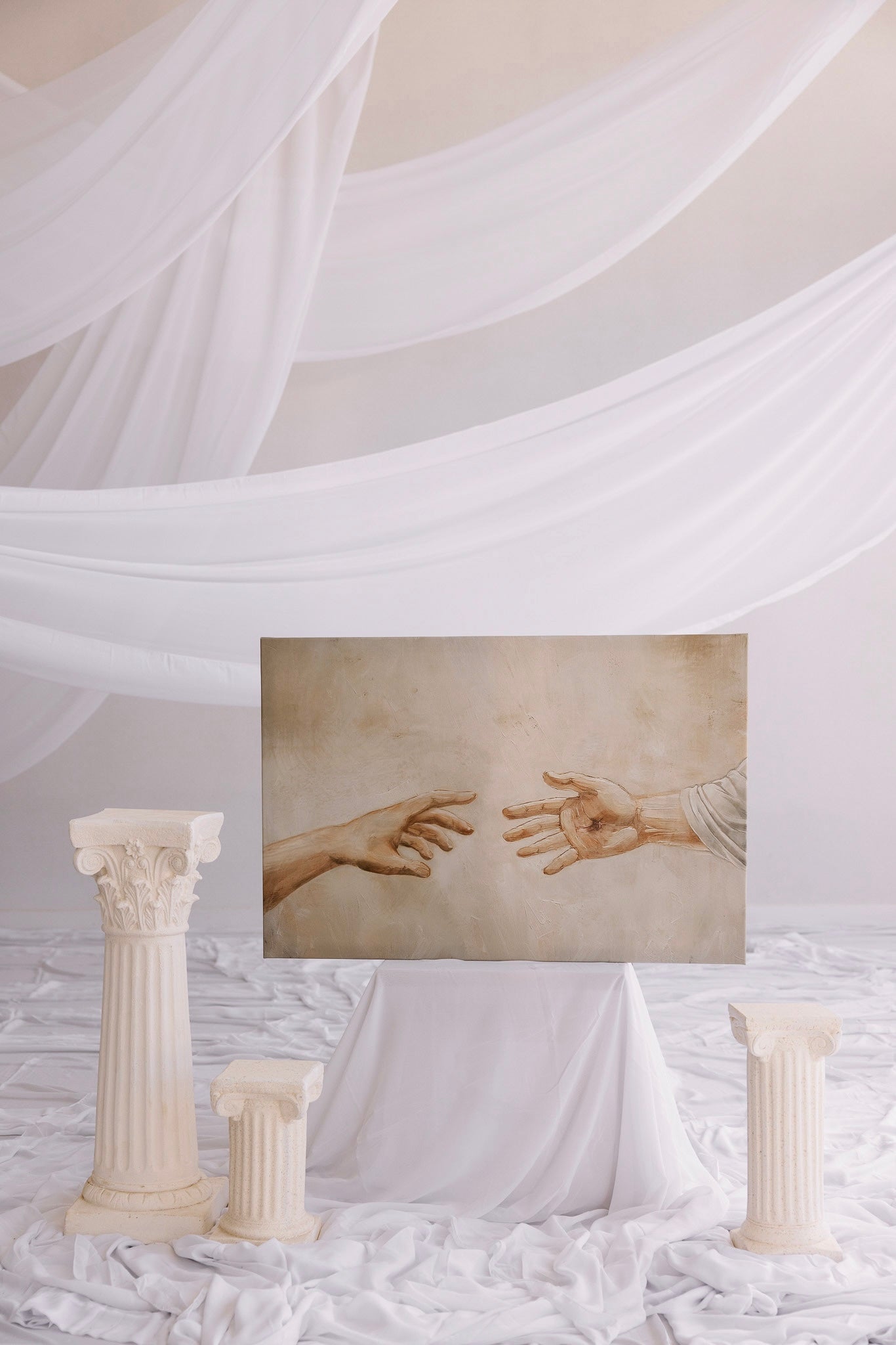 Artistic depiction of hands reaching towards each other with classical columns and draped fabric in the background. Reaching Out Canvas modern Christian wall art showing Jesus’ healing, by Christian artist. Christian michelangeloh art