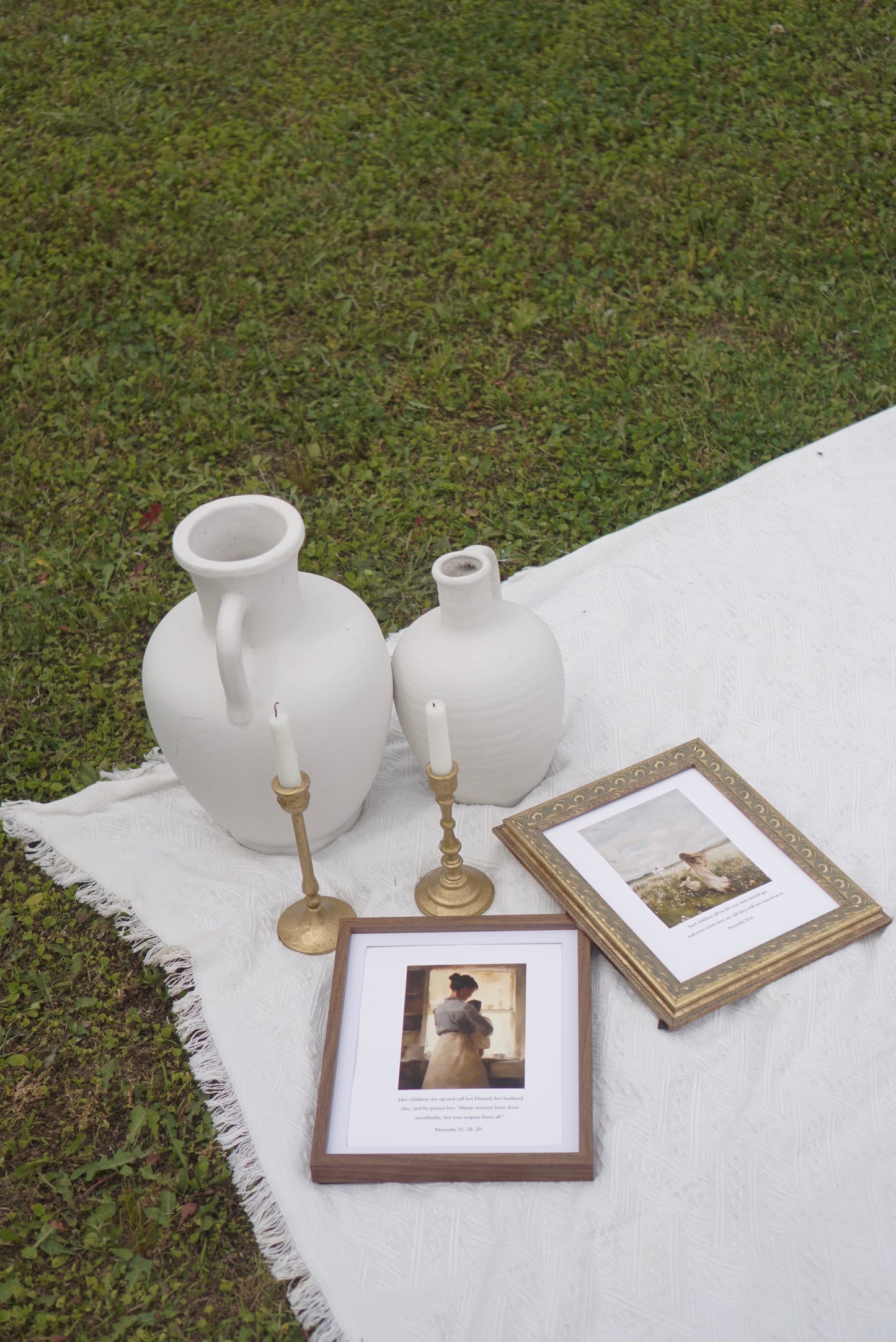 Decorative setting with white vases, framed photos, and candles on a white blanket outdoors. Proverbs 31 Scripture Print Christian wall art modern, faith-filled verse for home decor.
