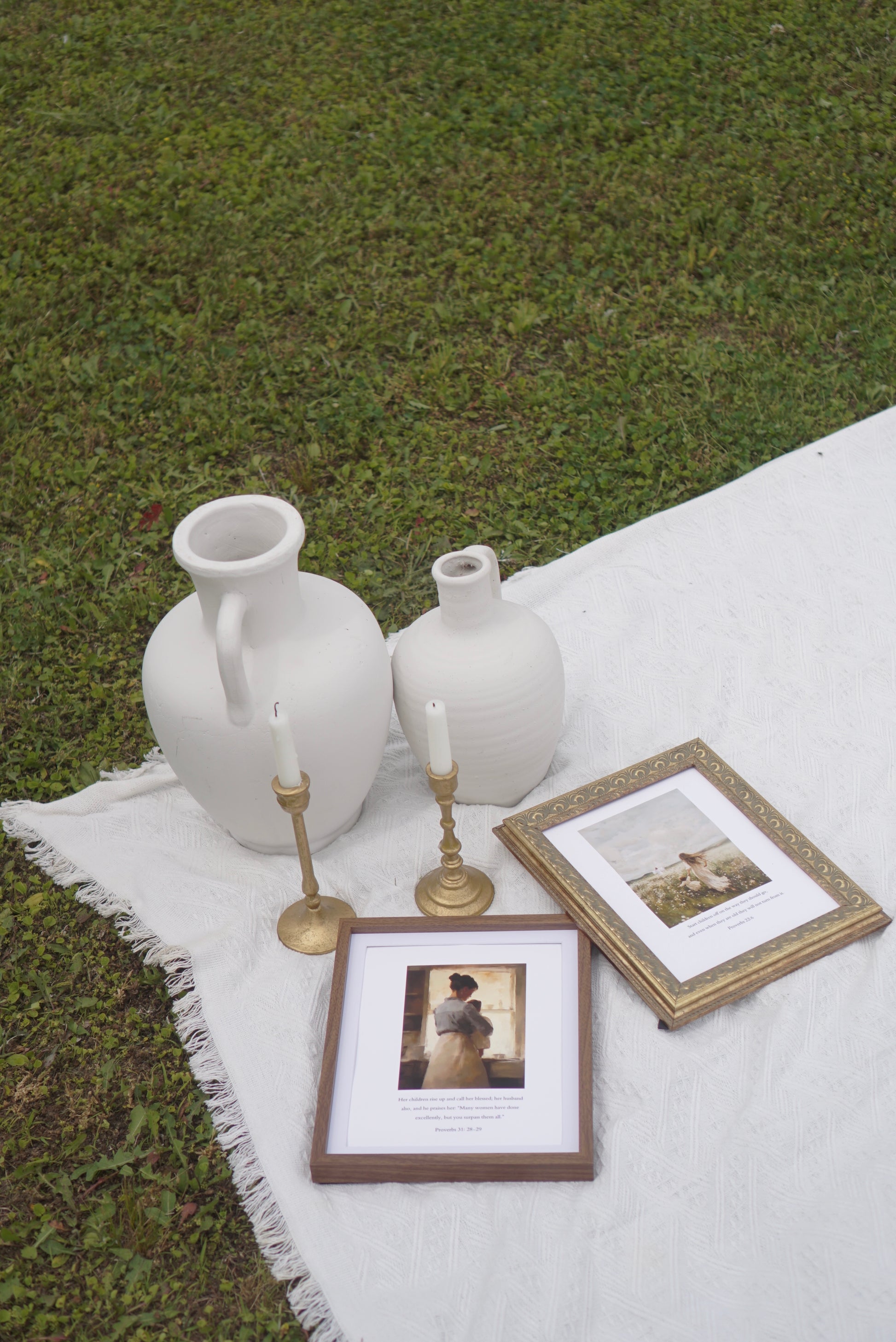 Decorative setting with white vases, framed photos, and candles on a white blanket outdoors. Proverbs 31 Scripture Print Christian wall art modern, faith-filled verse for home decor.