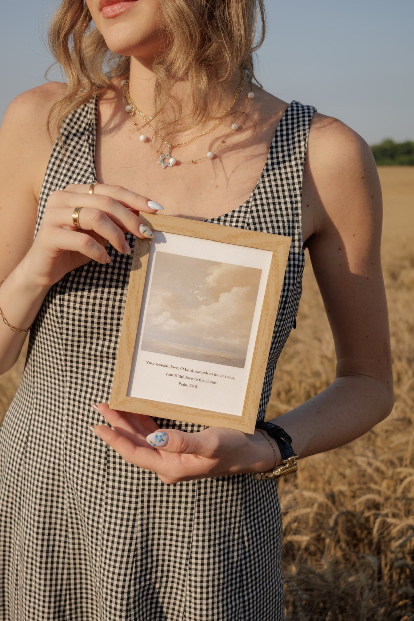 Steadfast Love Scripture Print Christian wall art modern, faith and devotion inspired. Woman holding a framed picture in a field